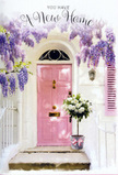 The photograph captures a doorway that looks as though it could belong to a welcoming Byfleet home, dressed thoughtfully to honour a fresh start. A pastel pink front door stands at the centre, its colour tender and warm, balancing between playful and sophisticated, much like the subtle charm of streets off Byfleet's village centre. The surrounding wall is whitewashed and calming, offering a simple backdrop that allows the details to shine. Above the door, generous strands of wisteria cascade down, their blossoms gathered in loose clusters of pale lavender and soft lilac. The flowers hang in layered curtains, some strands reaching lower than others, giving the impression of gentle movement and that soft, floral fragrance often noticed beside older houses and gardens near the River Wey. Resting on the doorstep is a grey tin bucket, chosen for its understated, slightly rustic feel. It overflows with plush white and cream roses, each bloom full and rounded, with layered petals that curl outward like small, luxurious cushions. Intermixed are sprigs of soft green foliage, peeking between the roses and softening the edges of the bouquet. Encircling the bucket, a blush-pink ribbon is tied neatly into a bow, its satin surface catching the light and echoing the pink of the door so that everything feels quietly coordinated. Sunlight filters through the leaves and wisteria above, casting gentle dapples across the flowers and step, lending a sense of warmth and time-of-day. The composition evokes the feeling of a thoughtful housewarming gesture in Byfleet: flowers placed on the step to greet someone as they arrive, carrying wishes for comfort, happiness, and the beginning of many cherished memories inside.